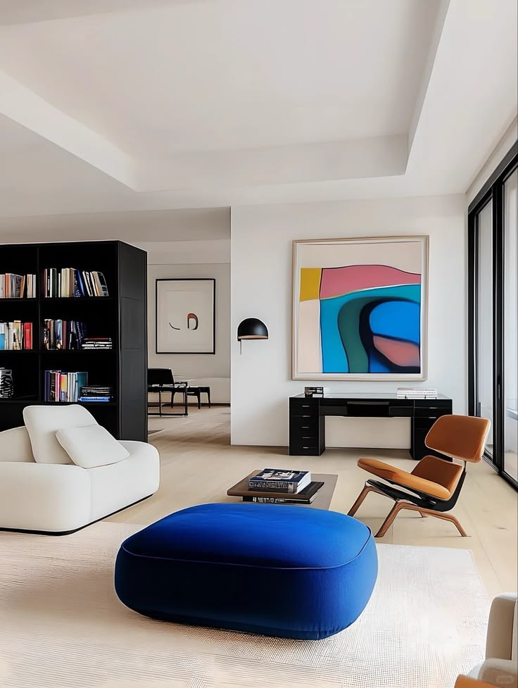 Modern art-filled interior with a vivid blue sculptural ottoman and abstract artwork